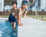 Photo of family having fun in the backyard pool. Kids are swimming.