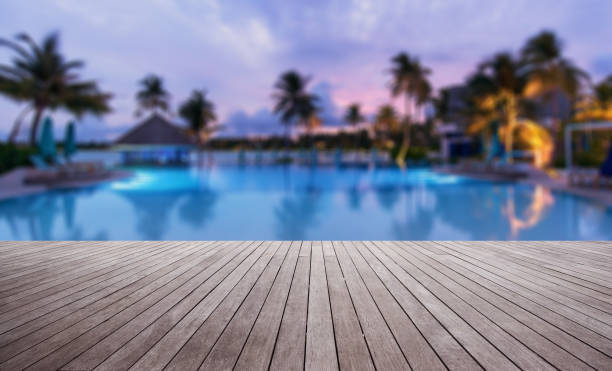 Wooden terrace beside tropical resort swimming pool at dusk Photo for the Superchlorination Blog Post. Shop at Swimart.